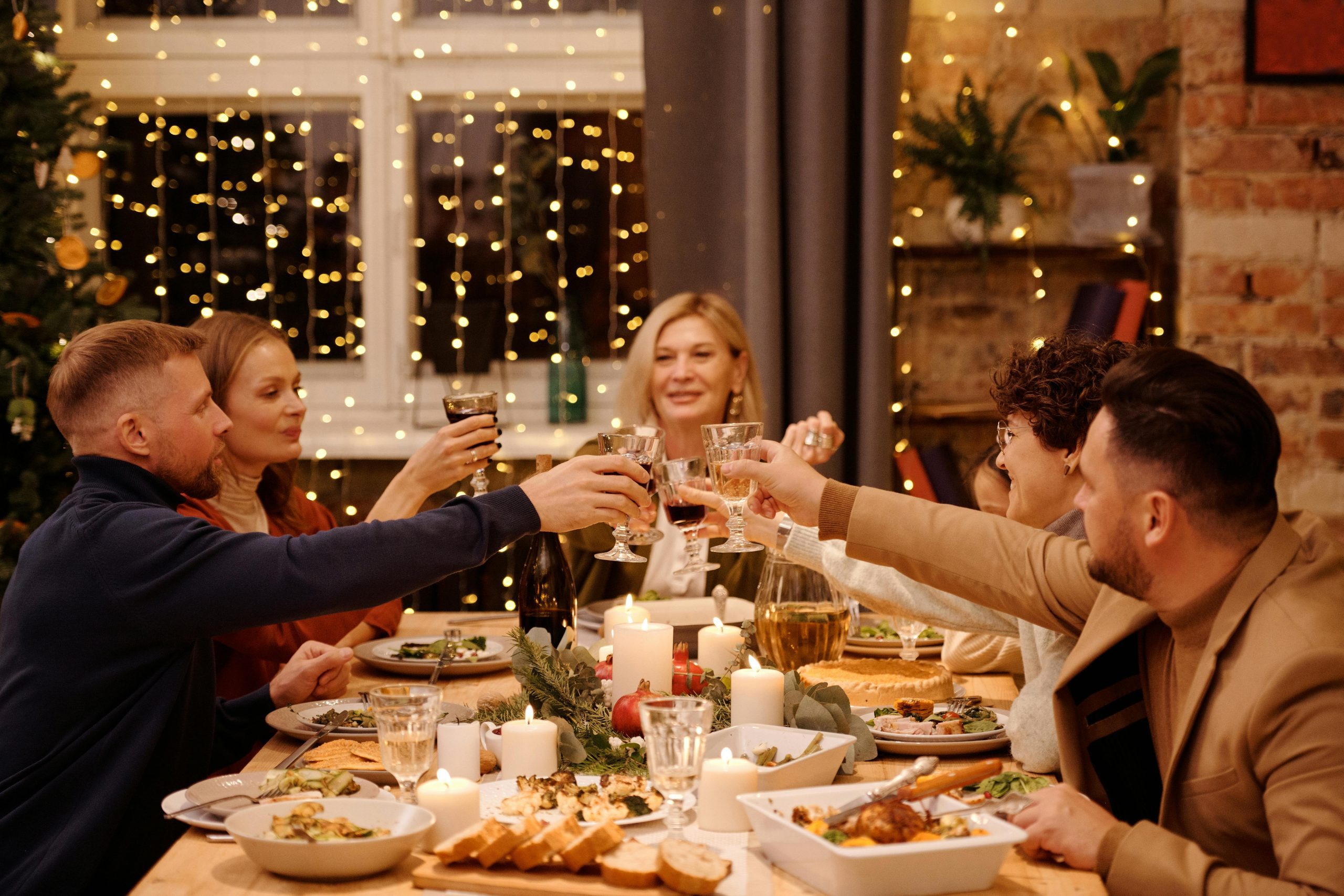 Amigos brindando em uma mesa de ceia farta de fim de ano, com foco em como evitar excessos nas festas de fim de ano e manter o equilíbrio.